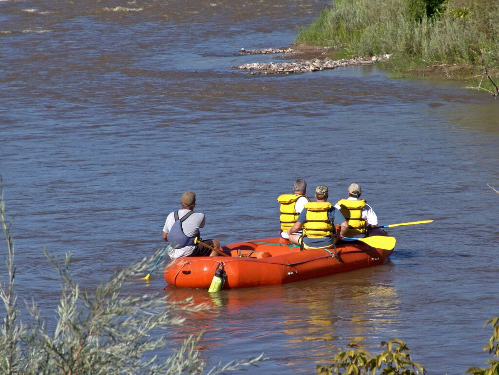 A raft floats on a smooth stretch of the Rio Grande River in New Mexico.