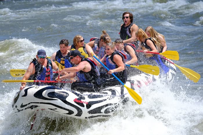 Group in a white and black raft paddling through rapids on the Yellowstone River