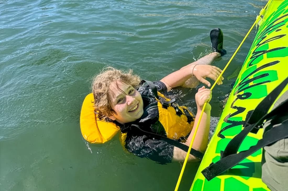 Young boy swims in the Yellowstone River, holding onto a raft