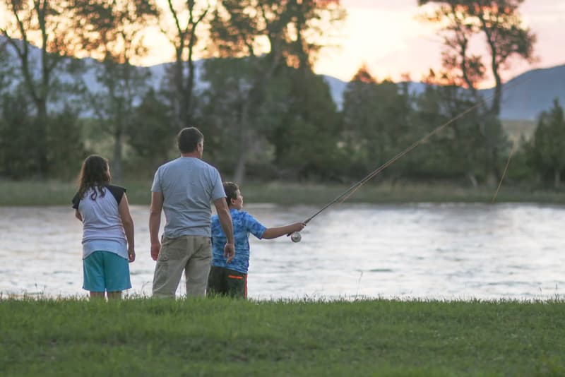 Father and two children fly fishing on the Yellowstone River at dusk.